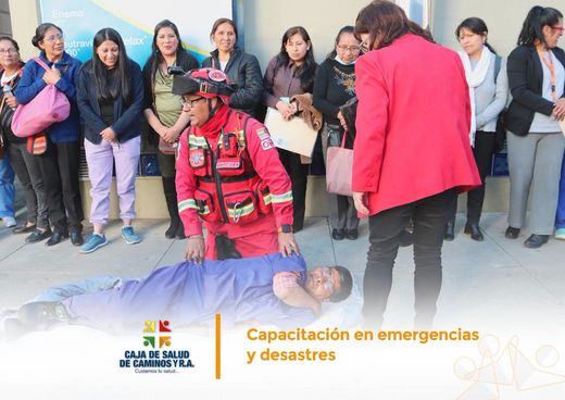 Un bombero practica la atención prehospitalaria con un compañero tendido en el suelo, frente al personal de la Caja que observa.