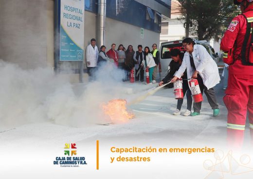 Personal con extintores entre el humo durante el simulacro de incendio en la calle frente al hospital.